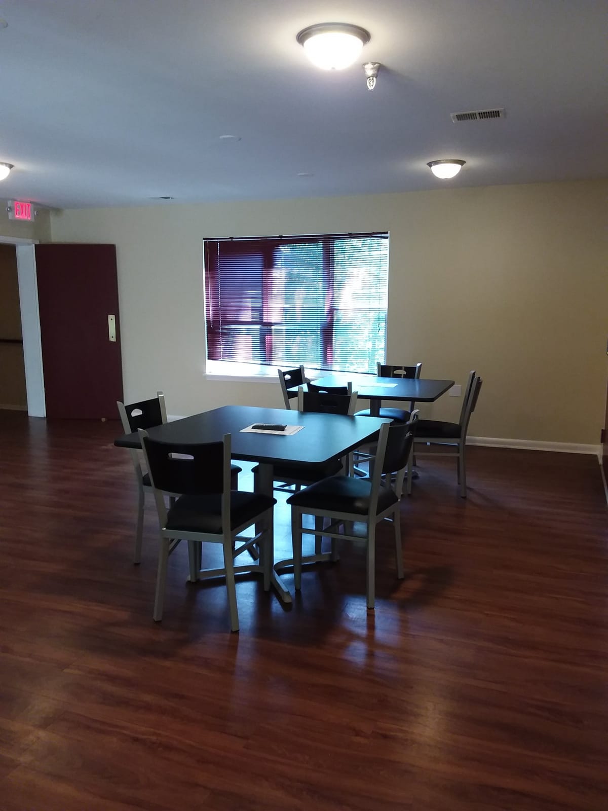 The community room at Indian Head Elderly Apartments, set with tables and chairs beside a blind-covered window