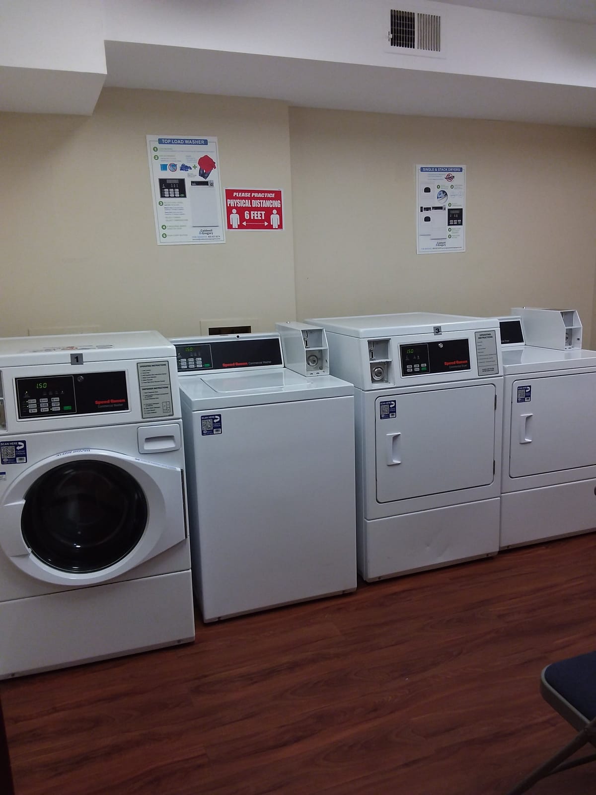The on-site laundry room at Indian Head Elderly Apartments, with washers and dryers along the wall and instruction signs posted above
